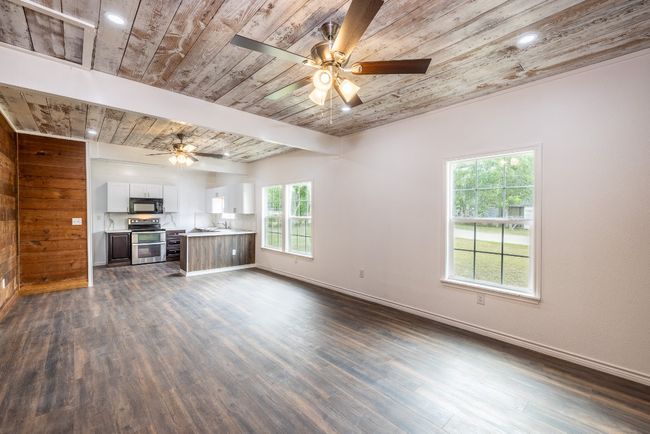 Unfurnished living room with baseboards, wooden ceiling, dark wood-style flooring, a sink, and ceiling fan | Image 5