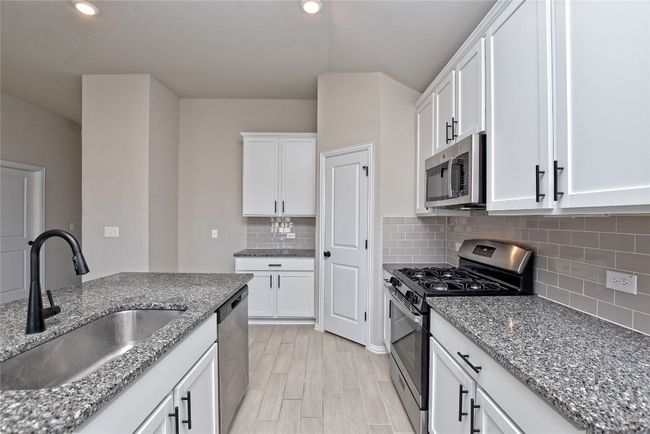 Kitchen with a sink, stone counters, appliances with stainless steel finishes, and white cabinetry | Image 11
