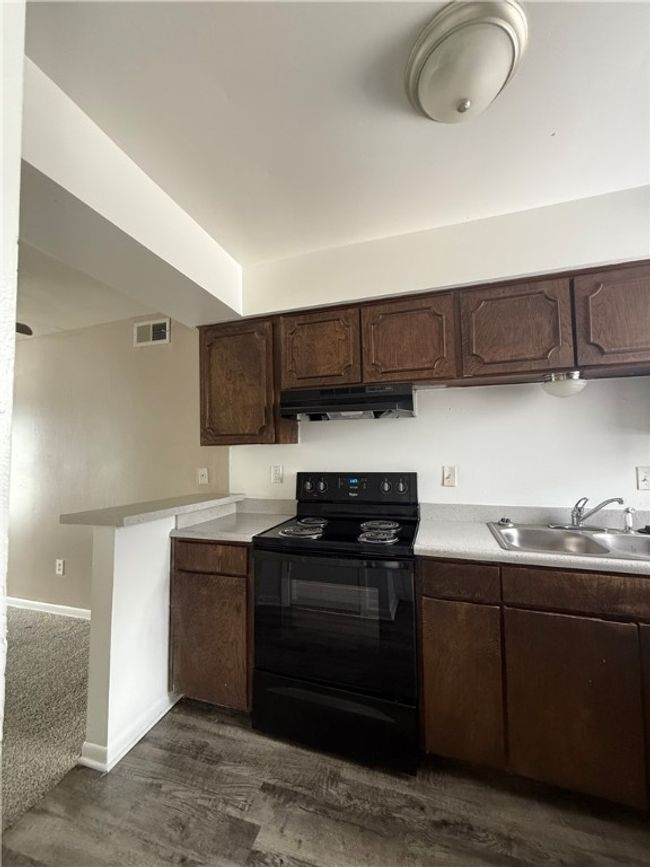 Kitchen with electric range, under cabinet range hood, and dark brown cabinetry | Image 4