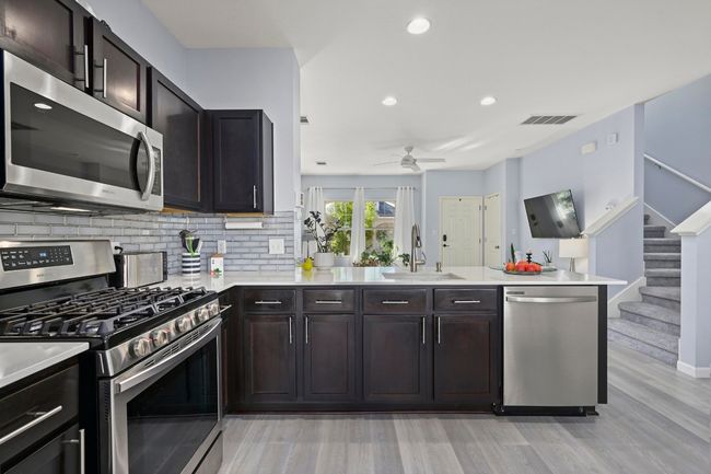 Kitchen featuring a sink, light wood-type flooring, visible vents, a ceiling fan, and appliances with stainless steel finishes | Image 17