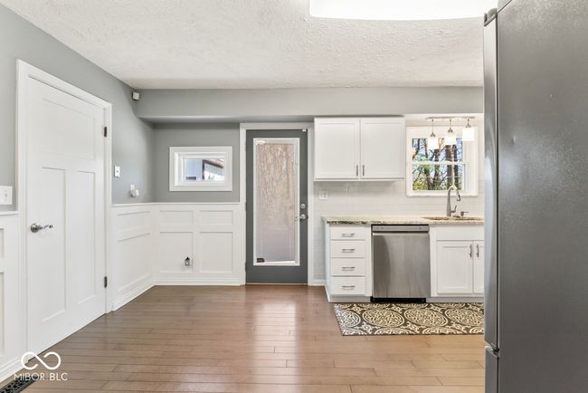 kitchen featuring white cabinets, wood-type flooring, a sink, and appliances with stainless steel finishes | Image 12