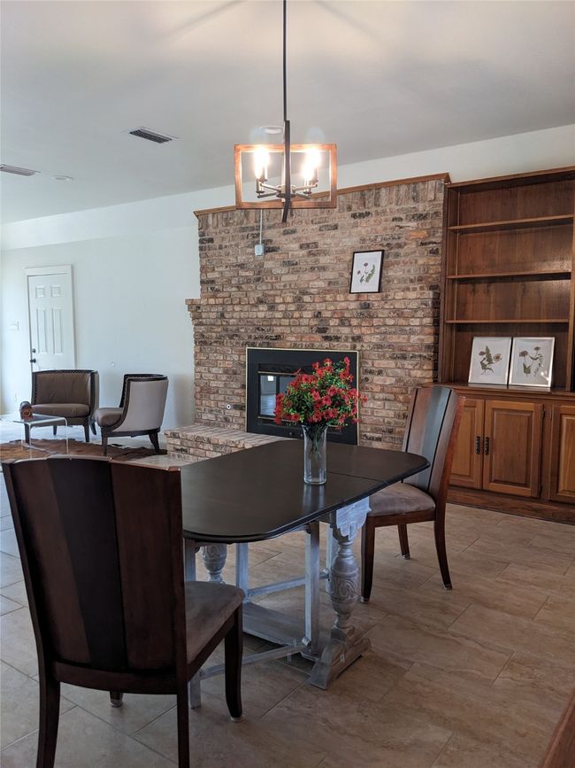 Dining area featuring a brick fireplace and a chandelier | Image 16