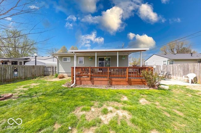 back of home featuring a yard, a fenced backyard, flower gardens, and a wooden deck | Image 6