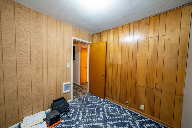 Unfurnished bedroom with wood walls, carpet floors, and heating unit | Image 19