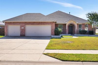 Single story home featuring a brick and stone elevation, and a 3 car garage. | Image 1