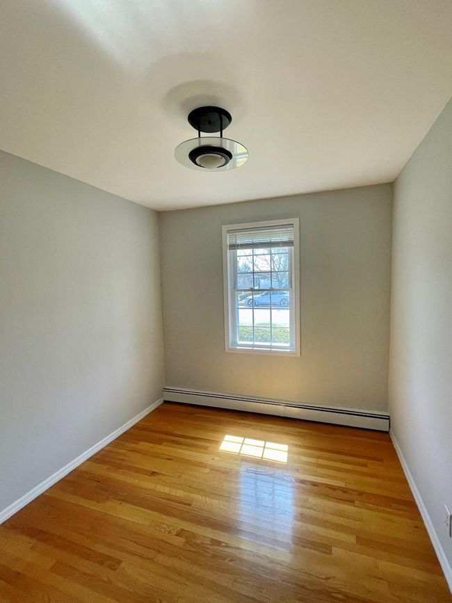 Empty room with baseboard heating, wood finished floors, and baseboards | Image 15
