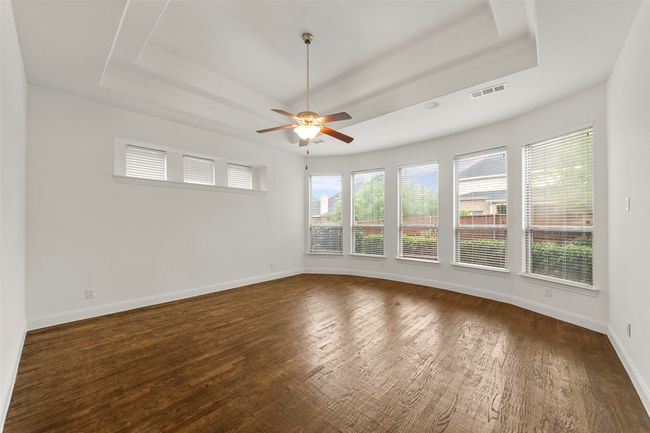 Spare room with visible vents, a ceiling fan, a tray ceiling, and dark wood-style floors | Image 16