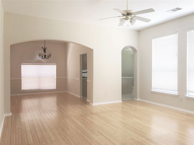 Unfurnished room with light wood-style flooring, a ceiling fan, arched walkways, and a chandelier | Image 4