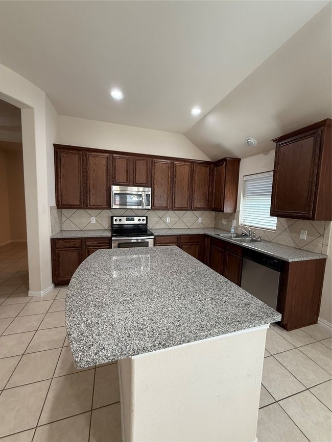 Kitchen featuring decorative backsplash, range, light tile patterned flooring, and dishwasher | Image 13