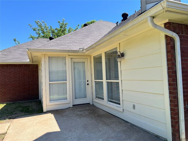View of exterior entry with brick siding, a patio area, and roof with shingles | Image 18