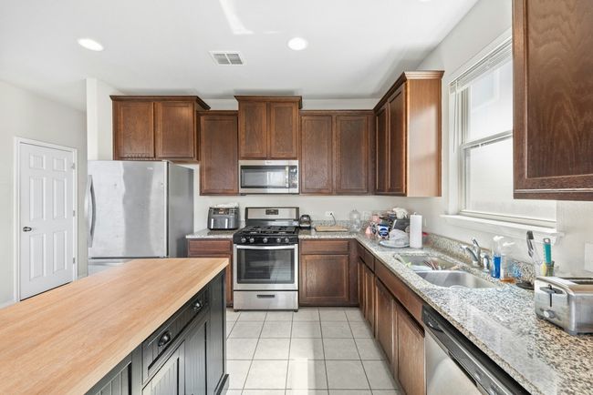 Kitchen featuring light tile patterned floors, visible vents, recessed lighting, a sink, and appliances with stainless steel finishes | Image 6