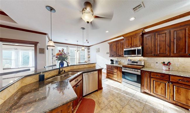 Kitchen featuring stainless steel appliances, a sink, visible vents, ceiling fan, and crown molding | Image 20