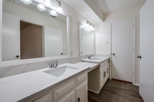 Full bathroom featuring double vanity, wood finished floors, and a textured ceiling | Image 14