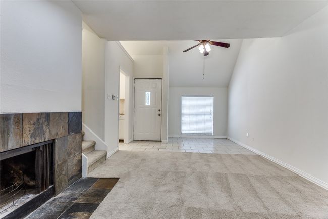 Tiled entryway featuring a tile fireplace, a ceiling fan, carpet floors, and stairway | Image 5