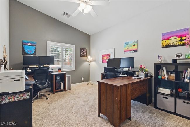 Office area featuring vaulted ceiling, ceiling fan, baseboards, carpet flooring, and visible vents | Image 23