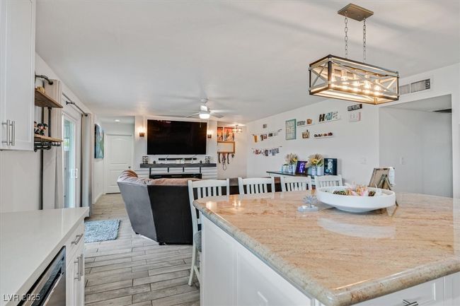 Kitchen featuring a ceiling fan, visible vents, wood finish floors, white cabinetry, and open floor plan | Image 7