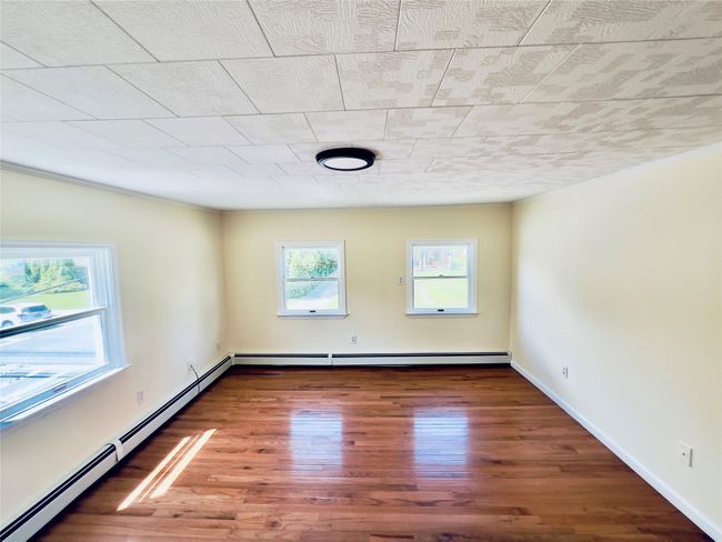 Empty room with baseboard heating and wood finished floors | Image 16