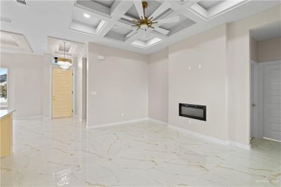 Unfurnished living room with beamed ceiling, coffered ceiling, and ceiling fan | Image 3