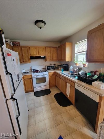 Kitchen featuring white appliances and sink | Image 2