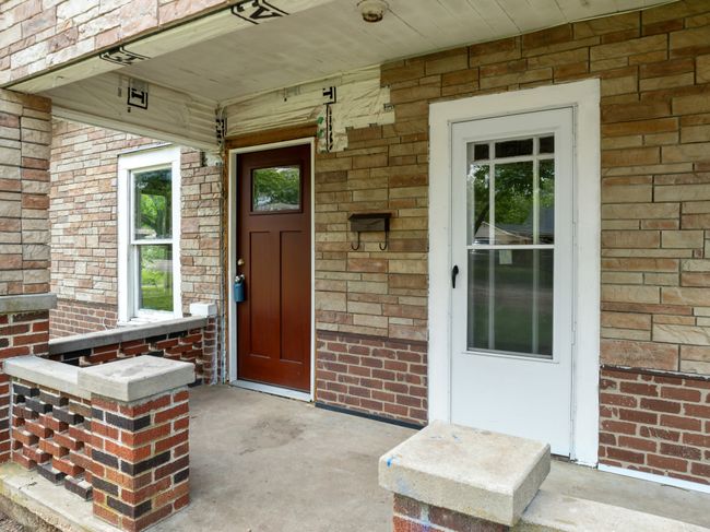 View of exterior entry with covered porch and brick siding | Image 5