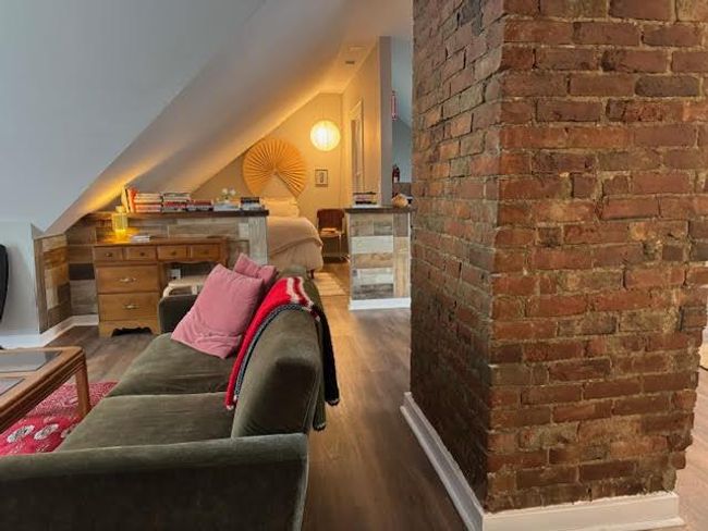 Bedroom featuring wood finished floors, vaulted ceiling, and brick wall | Image 28