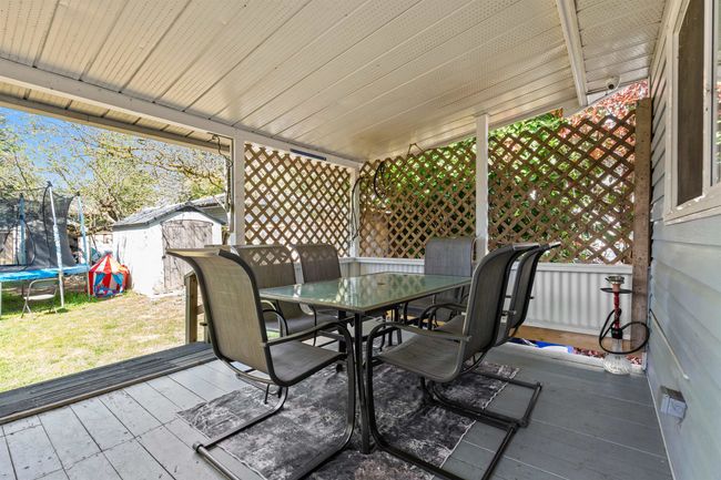 Deck featuring an outbuilding, a trampoline, a lawn, a shed, and outdoor dining area | Image 29
