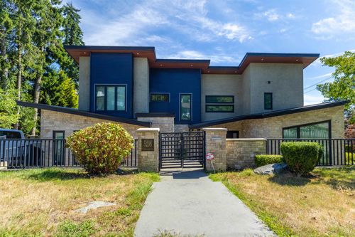 Contemporary home featuring a striking modern architectural design with mixed-material exterior combining dark blue paneling and warm brick detailing | Card Image