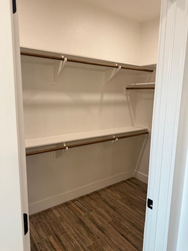 Walk in closet with dark wood-style flooring | Image 35