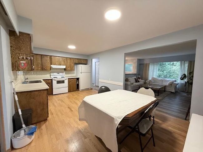 Kitchen featuring white appliances, under cabinet range hood, light wood finished floors, a sink, and light countertops | Image 14