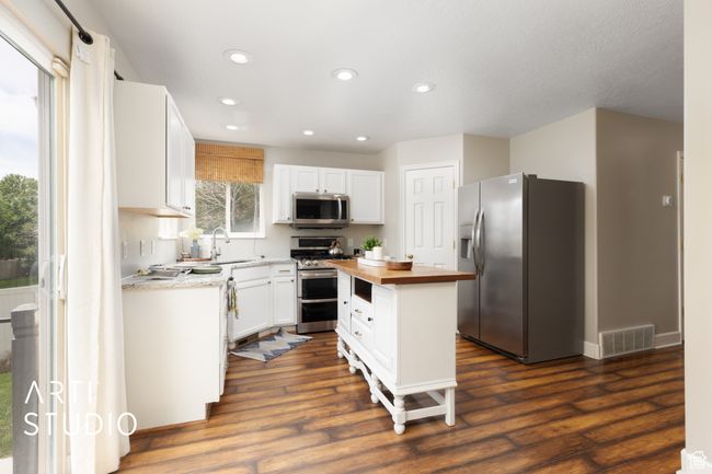 Kitchen featuring appliances with stainless steel finishes, butcher block countertops, recessed lighting, white cabinetry, and dark wood-type flooring | Image 6