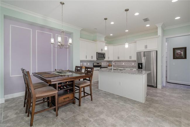 Kitchen featuring light stone countertops, stainless steel appliances, sink, decorative light fixtures, and white cabinetry | Image 8