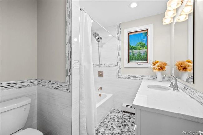 Bathroom featuring tile walls, a baseboard radiator, toilet, vanity, and recessed lighting | Image 24