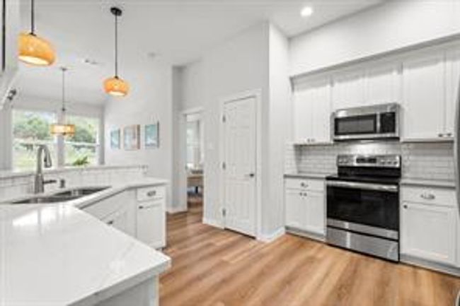 Kitchen with a sink, decorative backsplash, light countertops, appliances with stainless steel finishes, and pendant lighting | Image 11