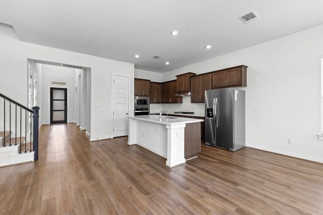 Kitchen with stainless steel appliances, a sink, light countertops, wood finished floors, and baseboards | Image 10