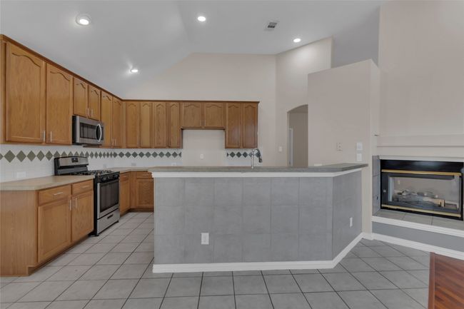 Kitchen with stainless steel appliances, arched walkways, light tile patterned flooring, light countertops, and backsplash | Image 18