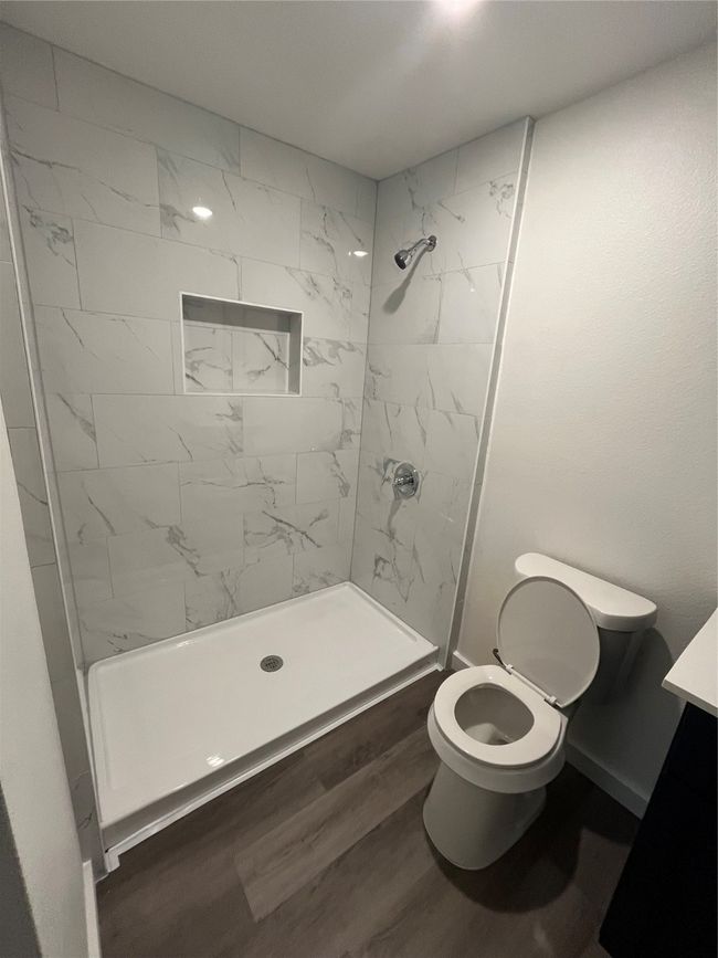 Bathroom featuring toilet, vanity, a stall shower, and wood finished floors | Image 4