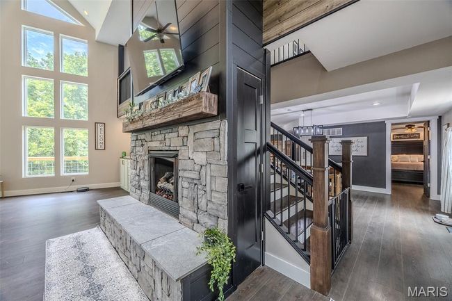 Staircase featuring a fireplace, wood finished floors, a ceiling fan, and a high ceiling | Image 14