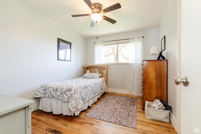 Bedroom featuring light wood-style flooring, baseboards, and a ceiling fan | Image 15