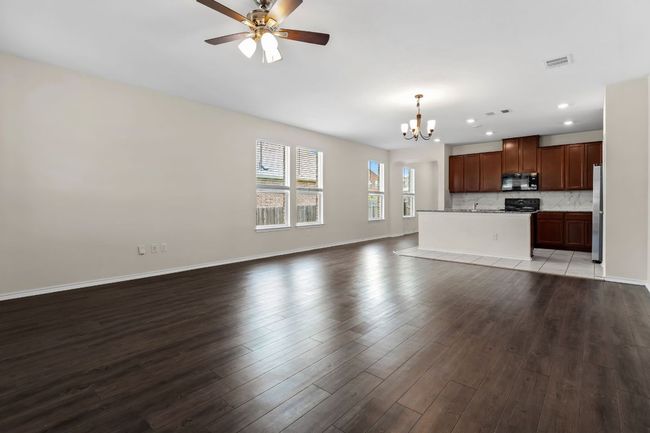 Unfurnished living room with a chandelier, wood finished floors, a ceiling fan, and recessed lighting | Image 13