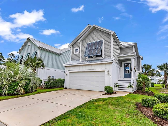 View of front facade featuring a garage, metal roof, driveway, a front yard, and board and batten siding | Image 16