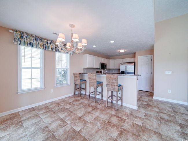 Kitchen with stainless steel appliances, a chandelier, a peninsula, white cabinets, and light countertops | Image 16