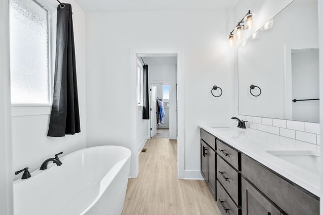 Full bath featuring plenty of natural light, wood finished floors, double vanity, and a freestanding tub | Image 17