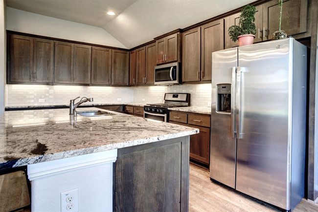 Kitchen featuring a sink, light wood-type flooring, dark brown cabinetry, stainless steel appliances, and lofted ceiling | Image 14