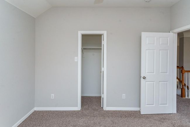 Unfurnished bedroom featuring baseboards, vaulted ceiling, a walk in closet, carpet floors, and a closet | Image 22