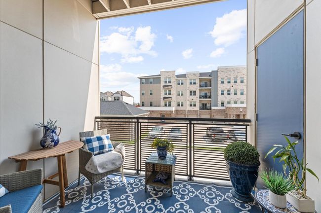 Enjoy fresh air and morning coffee from your covered balcony—complete with decorative flooring, cozy seating, and a peaceful courtyard view. | Image 11