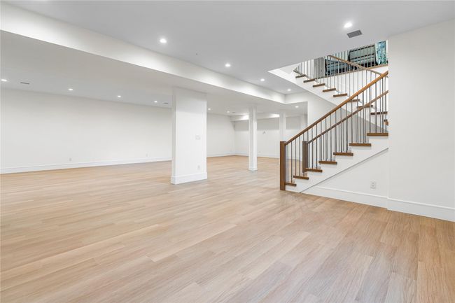 Finished below grade area featuring light wood-style flooring, stairs, baseboards, and recessed lighting | Image 39