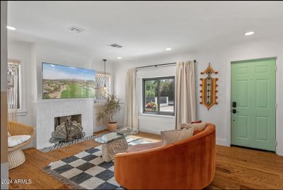 The living room is warm and inviting, featuring a cozy fireplace framed by sleek tiles. The hardwood floors add a touch of elegance, with their rich, dark finish that complements the space. | Image 2