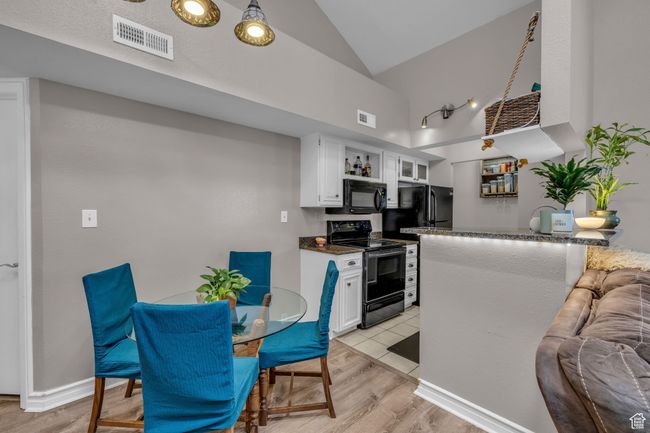 Kitchen with white cabinets, light wood-type flooring, visible vents, and black appliances | Image 5