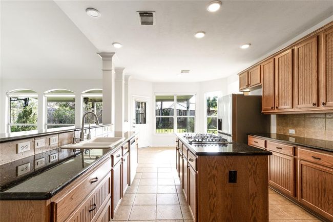 Kitchen with abundant cabinet space, a center island with cooktop, and lovely views of the backyard make this both practical and inviting. | Image 11
