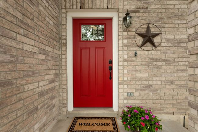 Charming entryway to the property, showcasing elegant brick siding and a striking red front door. | Image 4